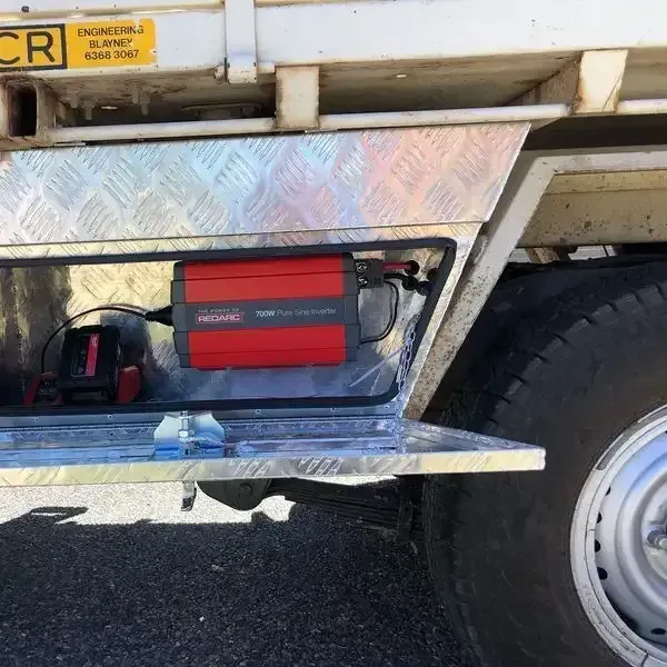 A Red Inverter Is Sitting Inside Of A Metal Box On The Side Of A Truck — REM Auto Electrics In Cardiff, NSW