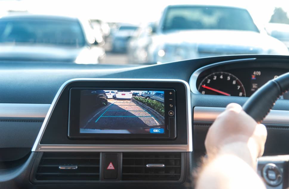 A Person Is Driving A Car With A Rear View Camera — REM Auto Electrics In Cardiff, NSW