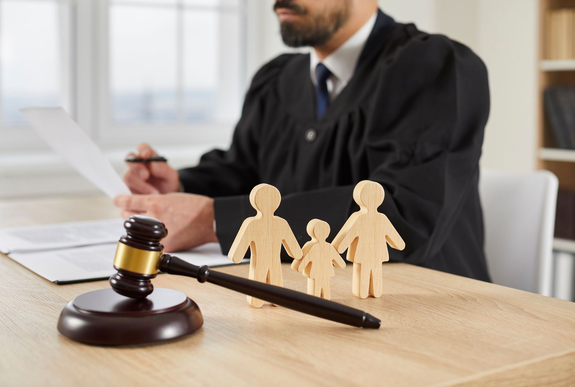 Judge with gavel, family figurines, and documents on desk
