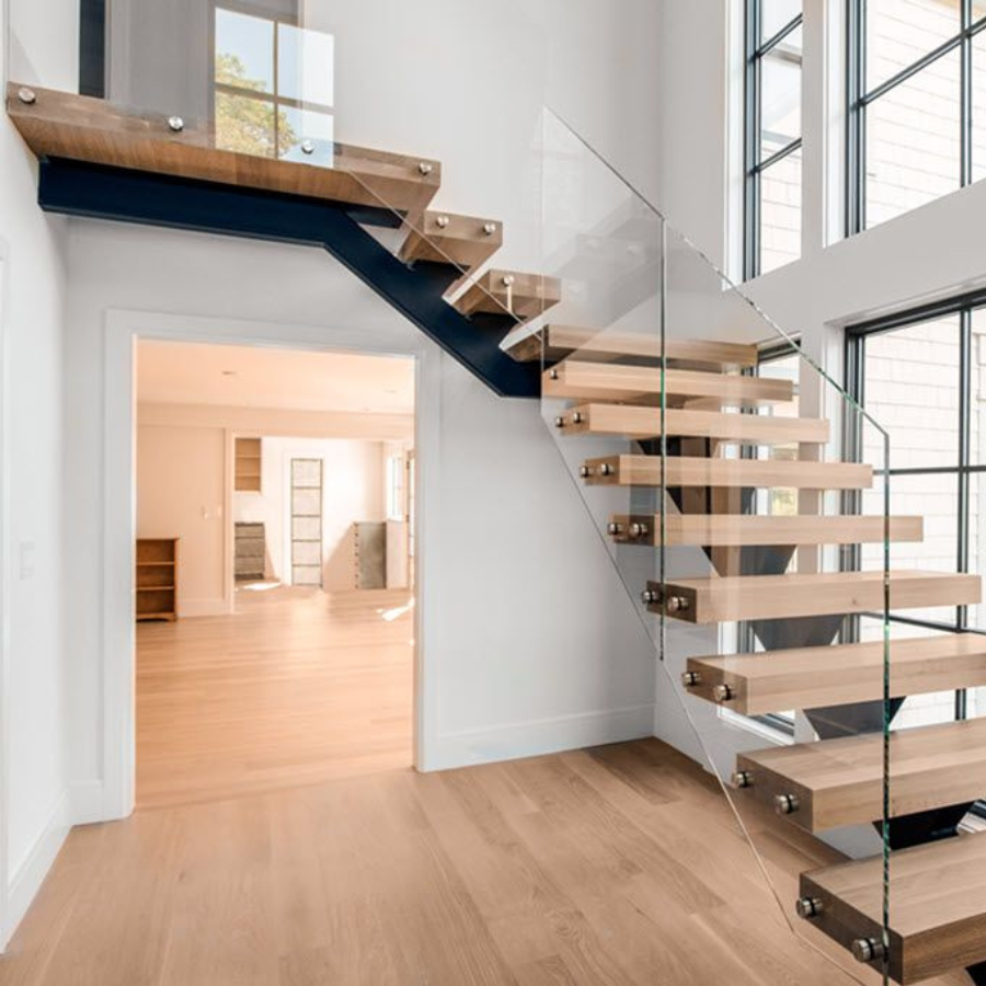 A wooden staircase with a glass railing in an empty room