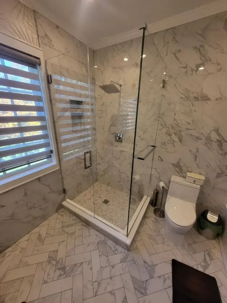 A bathroom with a walk in shower , toilet , and window. - glass shower enclosures