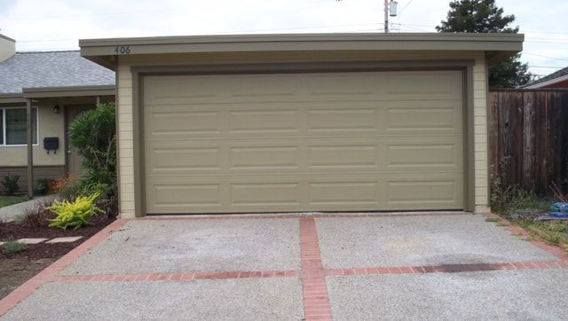 Single-car garage with beige door and concrete driveway in a suburban home exterior.