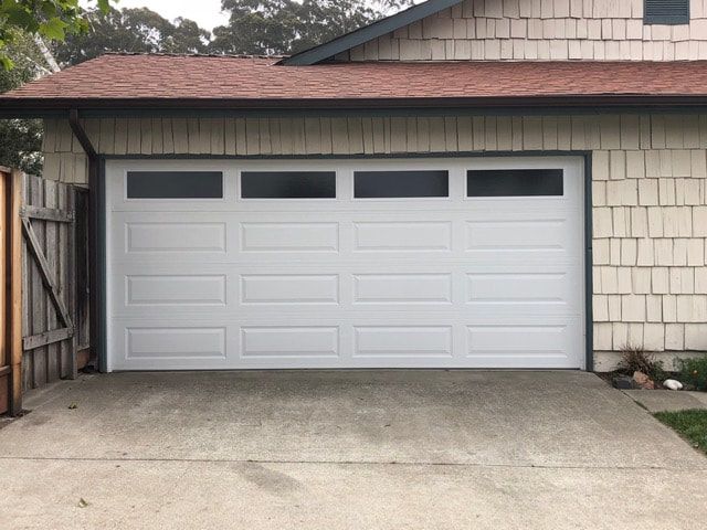 White two-car garage door with small windows in a house exterior driveway