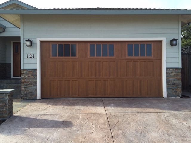 Two-car brown garage door on a house with stone accents and driveway