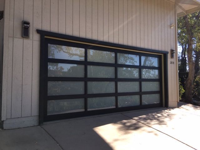 Black-framed glass garage door on a beige house exterior in daylight