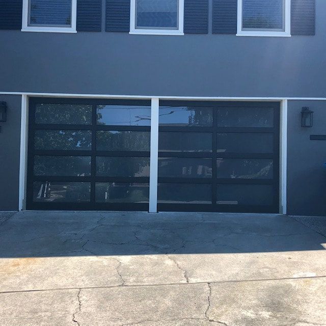 Modern building facade with two dark glass garage doors and windows above.