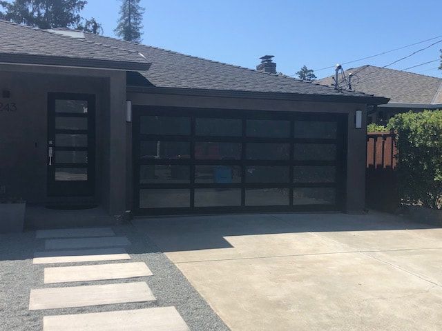 Modern house exterior with a dark garage door and concrete driveway in bright sunlight