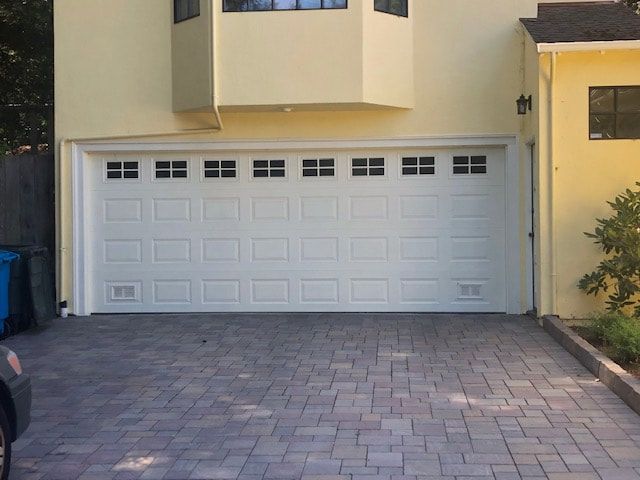 White double garage door on a beige house with a paved driveway.