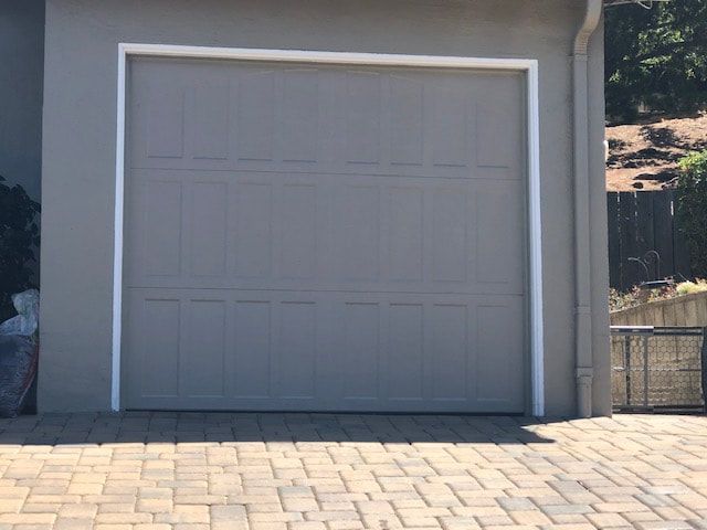 Closed white garage door beside a paved driveway in front of a house