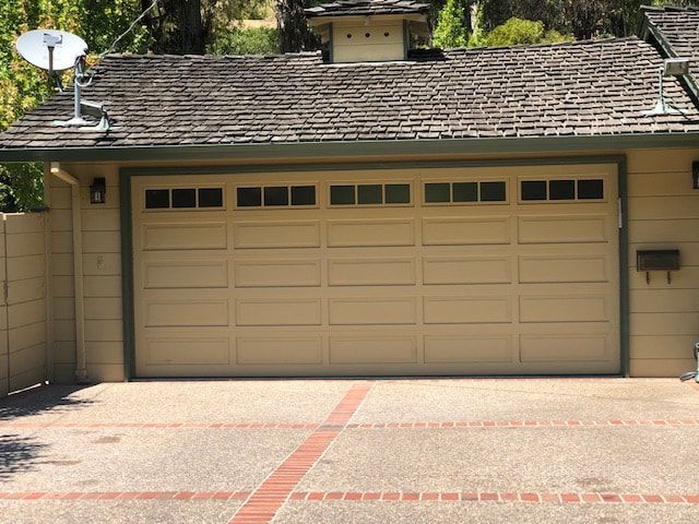 Tan house with a two-car garage, shingled roof, and driveway in front