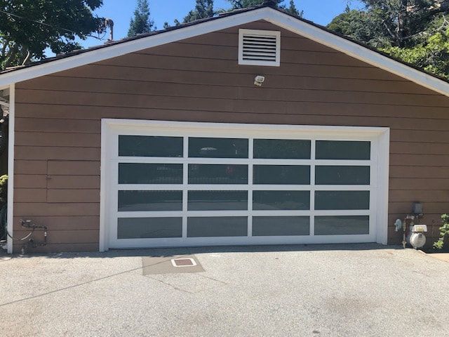 Brown garage with a white-framed glass door and driveway in front