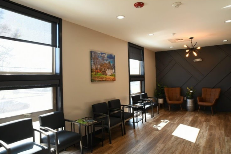 A waiting room with chairs and a painting on the wall.