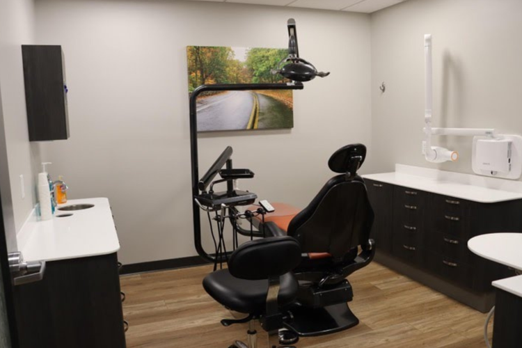 A dental office with a dental chair and a painting on the wall.