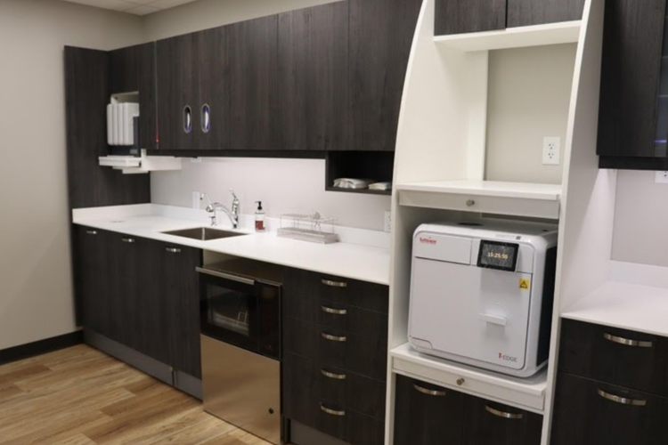 A kitchen with a sink , microwave , and a machine on the counter.