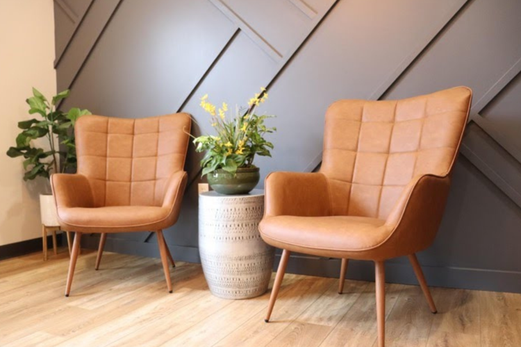 Two brown leather chairs are sitting next to each other in a room.