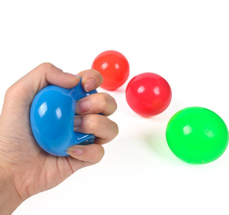 A hand is holding a blue ball in front of three red and green balls