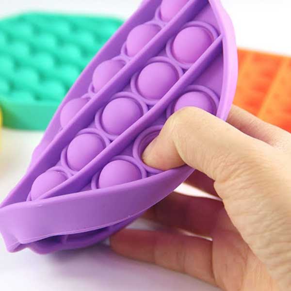 A person is holding a purple pop it toy in their hand.