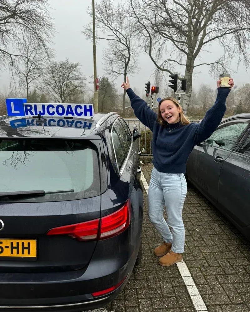 Een lachend persoon staat naast een auto met een blauw