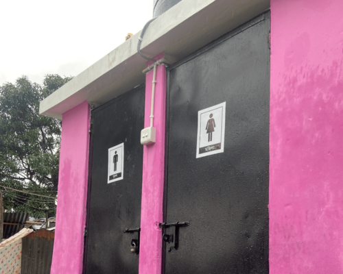 Pink restroom entrance with black doors marked male and female symbols