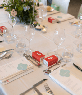 Set table with wine glasses, silverware, napkins, and red favor boxes at a formal event