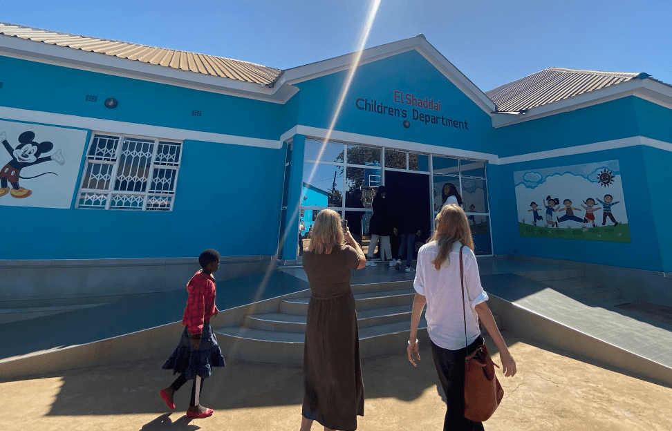 People walking toward a bright blue building entrance on a sunny day