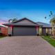 Modern single-story house with a gray garage, gravel driveway, and blue evening sky