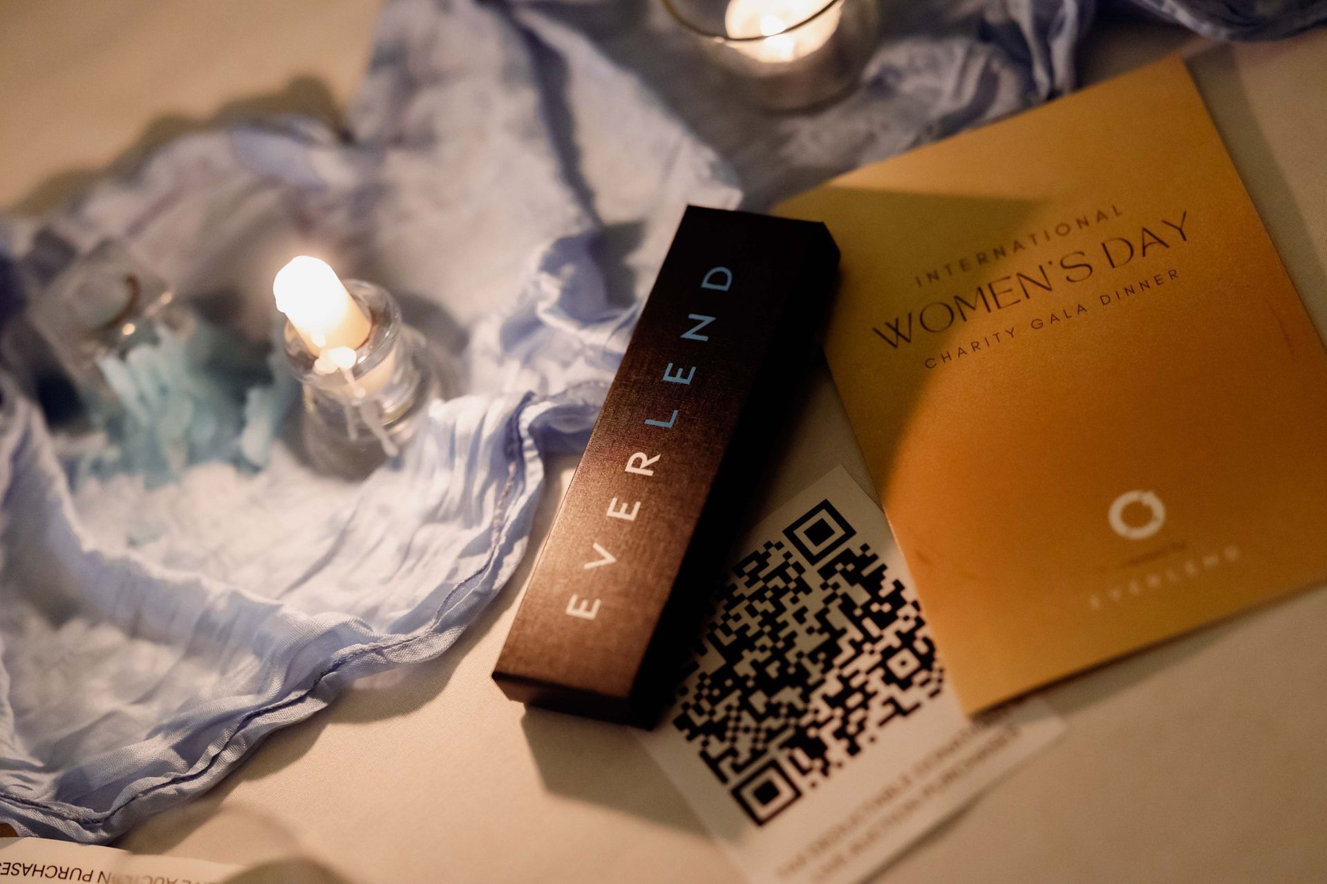 EverLend gift box and gala program on a candlelit table at the International Women's Day Charity Gala
