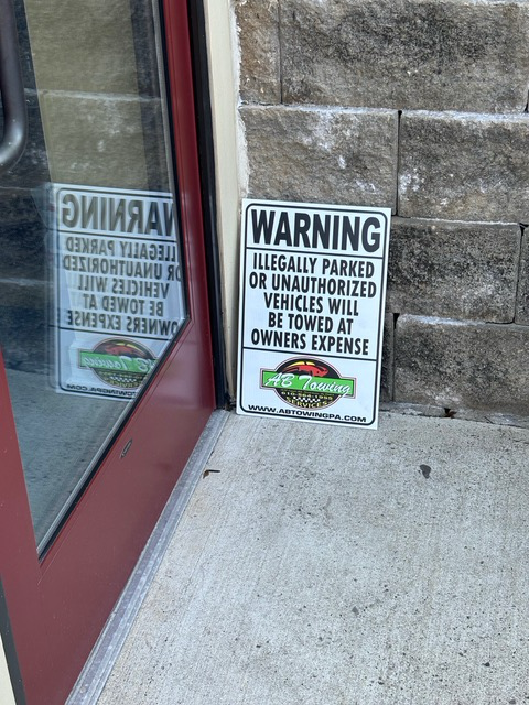 A sign that says warning illegally parked or unauthorized vehicles will be towed at owners expense