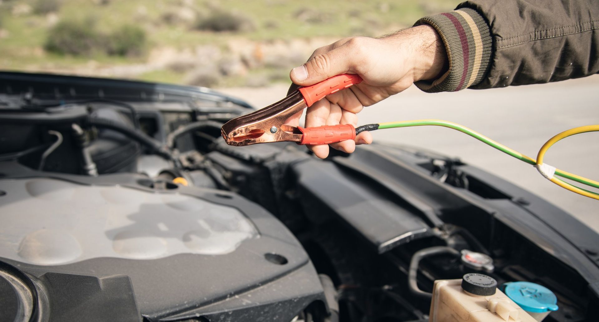 A person is charging a car battery with a jump starter.