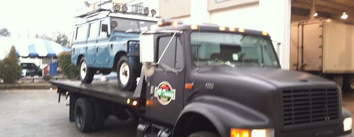 A blue land rover is being towed by a tow truck