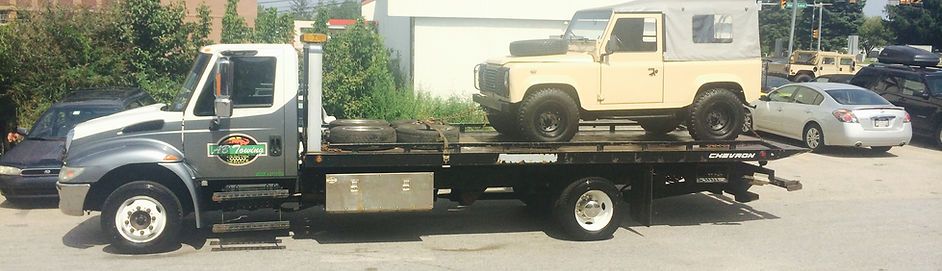 A tow truck with a jeep on the back of it