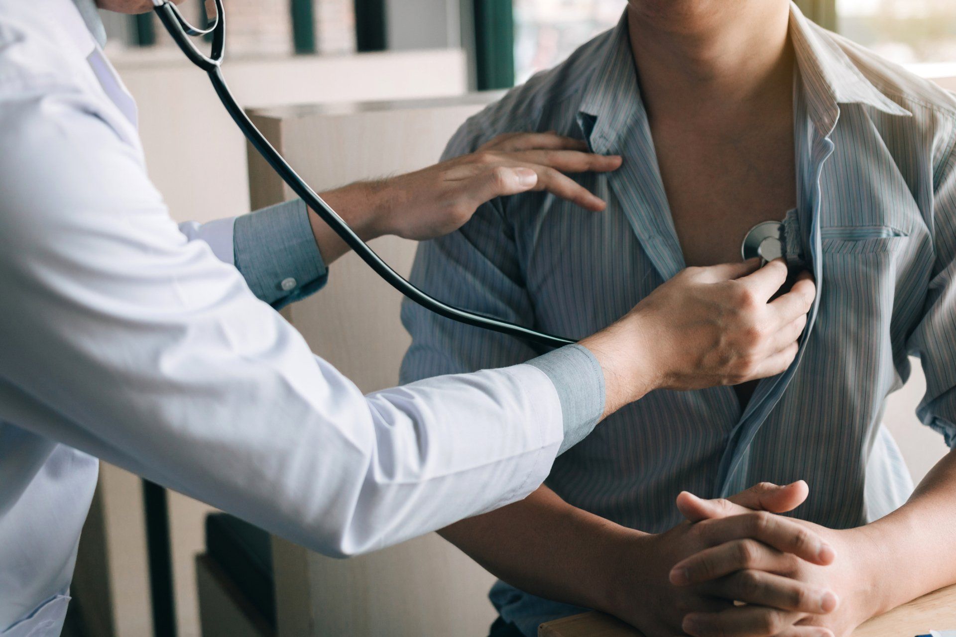 A doctor is listening to a patient 's heart with a stethoscope.