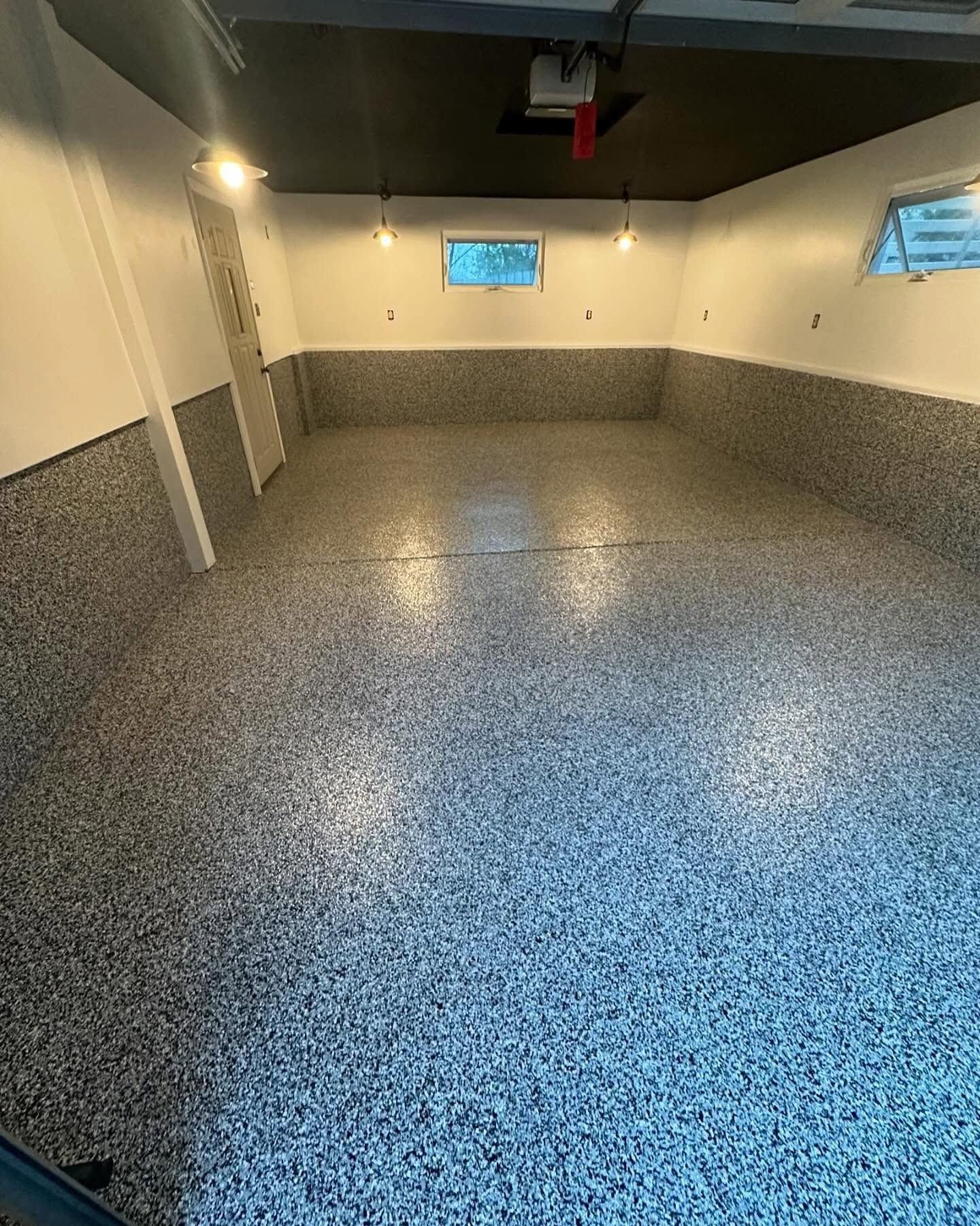 Empty garage with speckled gray epoxy floor and small windows on the back wall