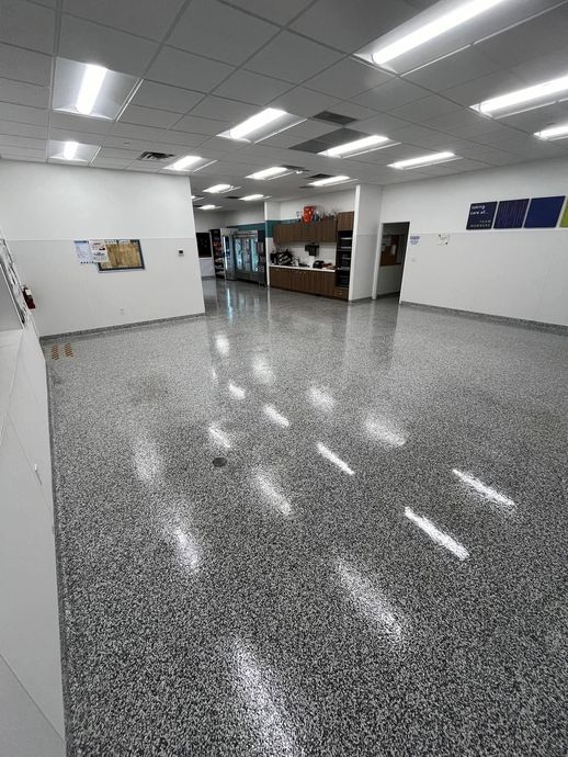 Empty tiled lobby with fluorescent ceiling lights and a reception desk in the distance.