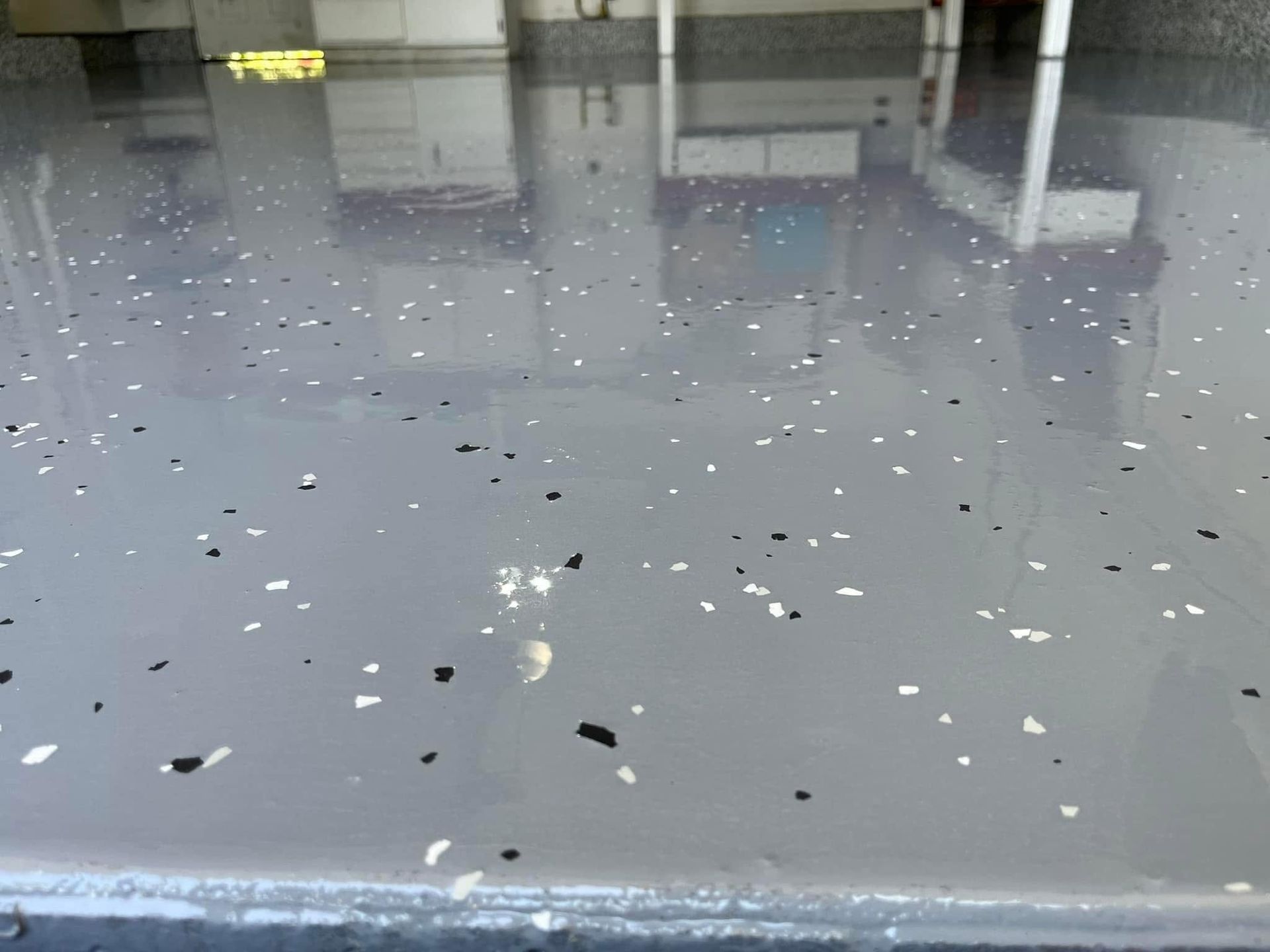 Shiny gray floor with scattered white debris and reflections in an indoor space