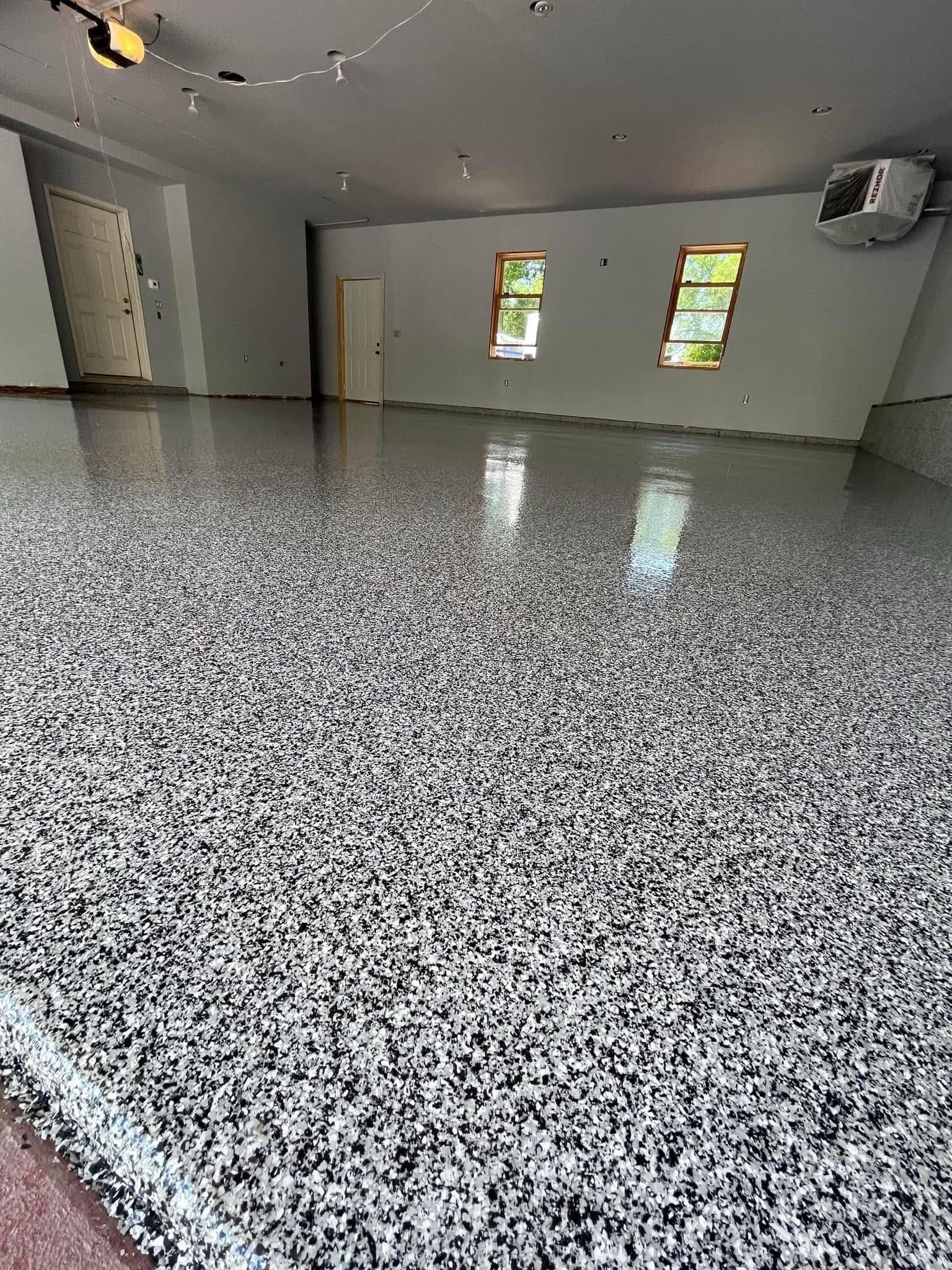 Empty room with speckled epoxy floor, white walls, windows, and ceiling lights.