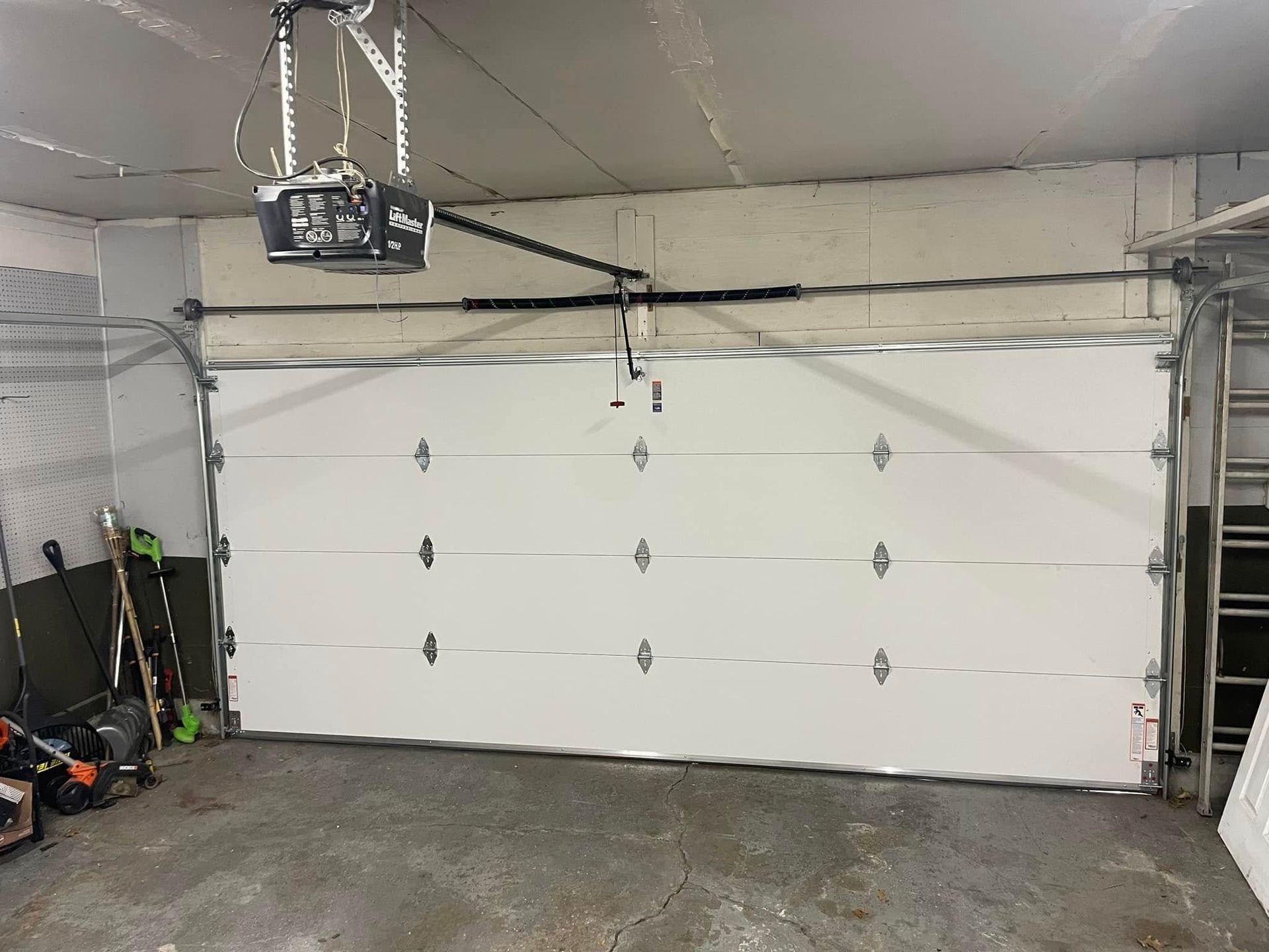 Empty garage with closed white sectional door and overhead opener