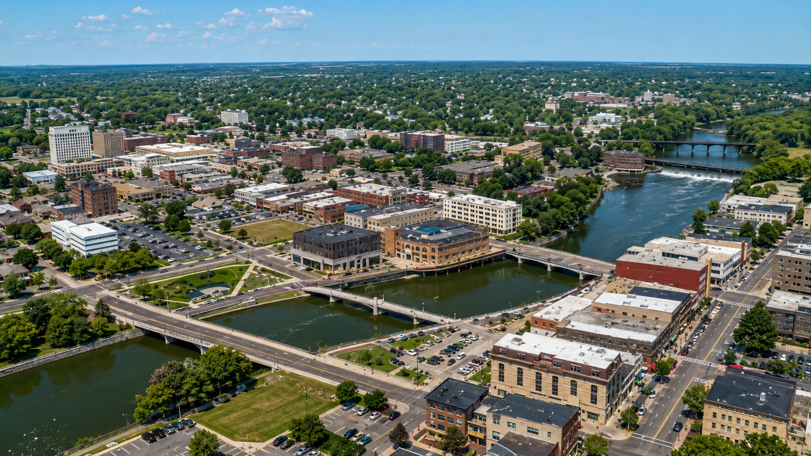 Aerial view of a riverfront town with bridges, buildings, and canals under a clear sky