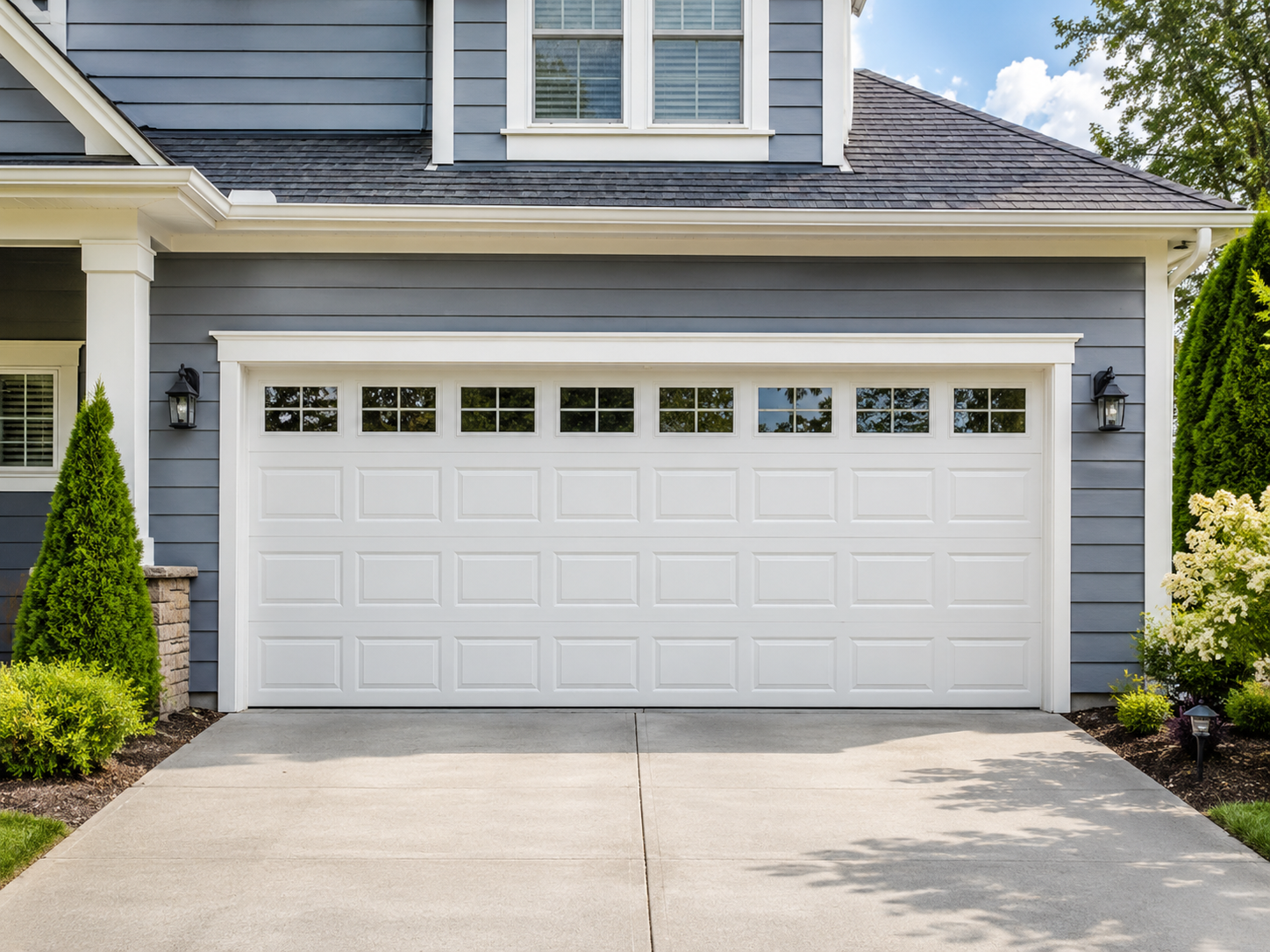 White two-car garage with gray siding and a concrete driveway in front of a house