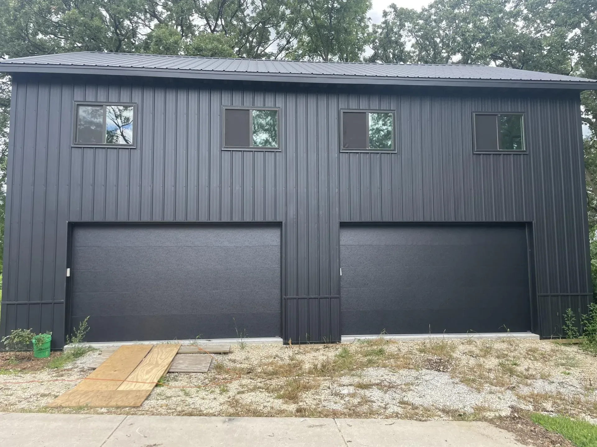 Black garage doors installed on a dark metal residential garage building