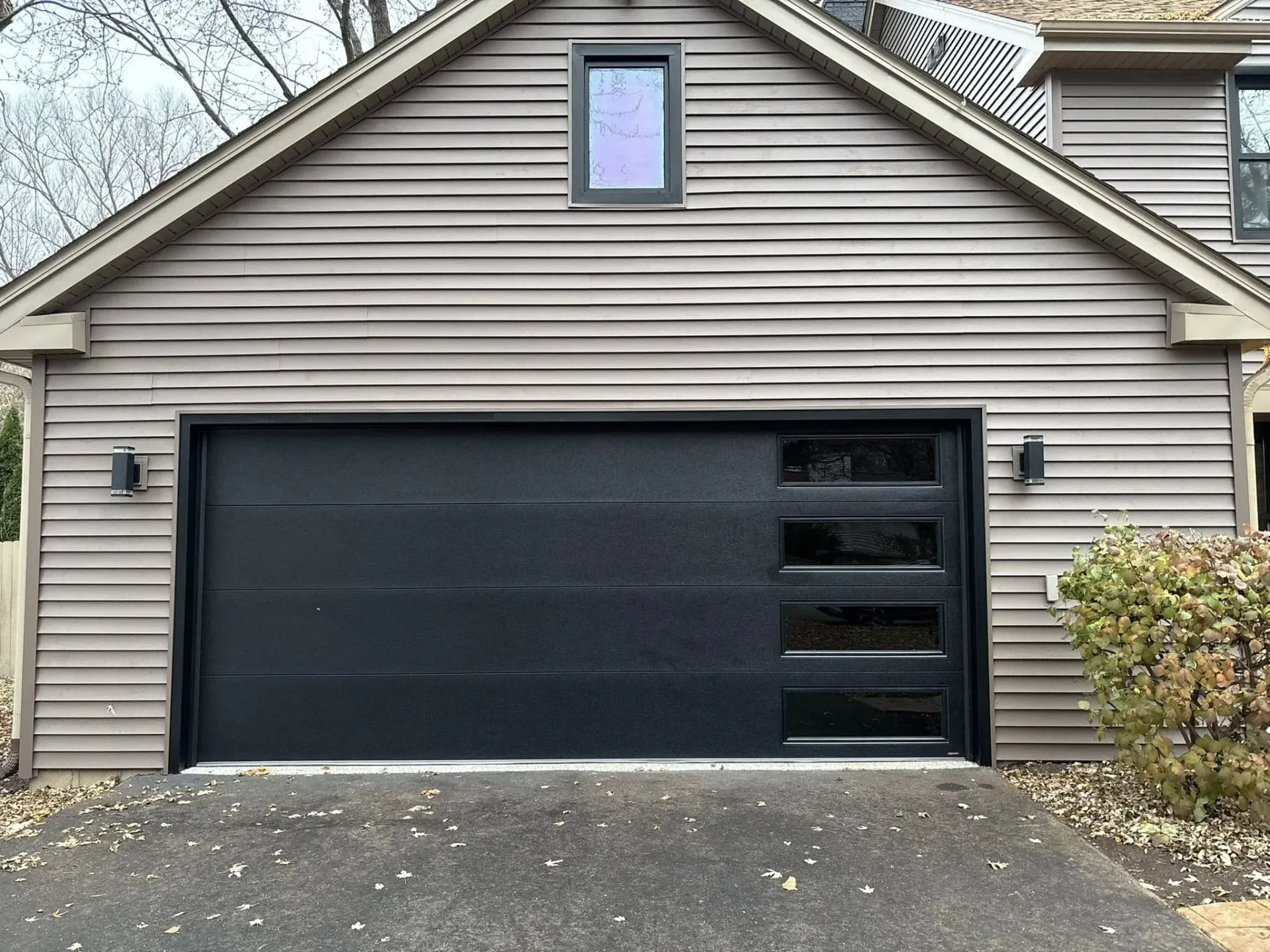 Black modern garage door with vertical side windows on a residential home in Roscoe IL