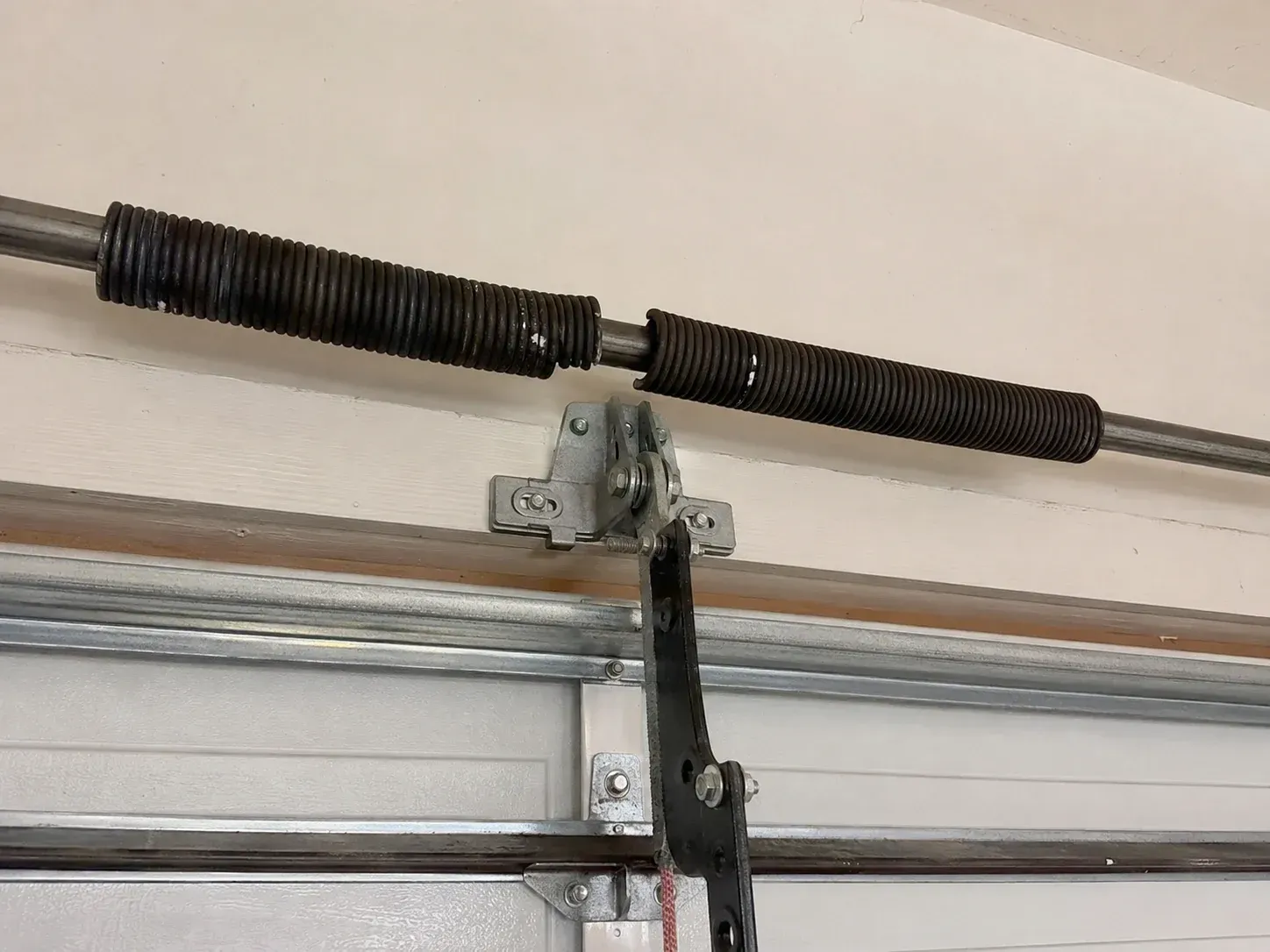 Broken garage door torsion spring needing repair on a residential overhead door system 