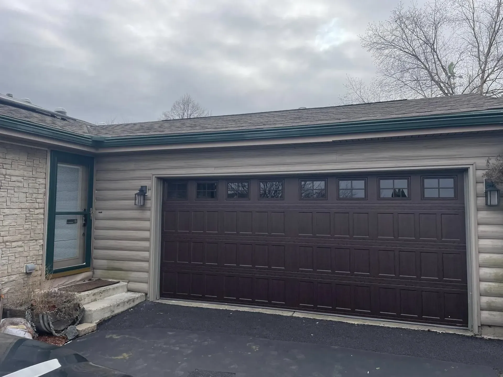 Brown wood-look garage door with upper windows on a residential home in Roscoe IL