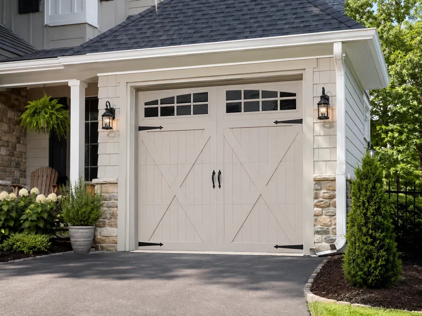 Carriage house style steel garage door with decorative hardware on a residential home