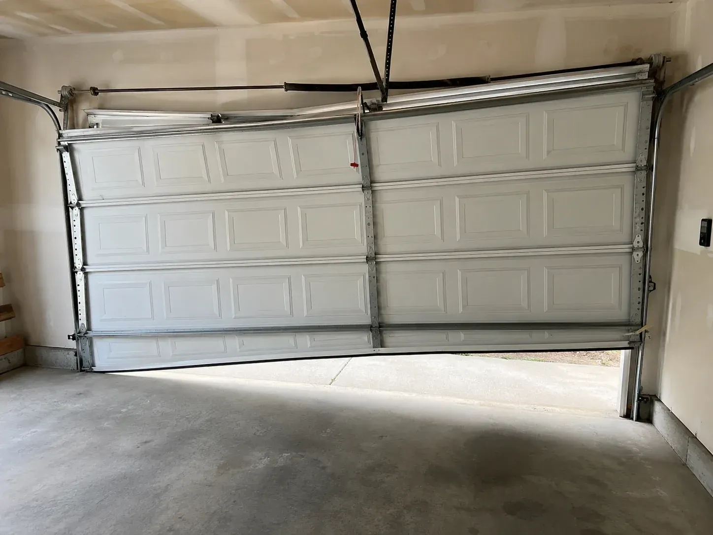 Residential garage door off track and stuck open inside a garage