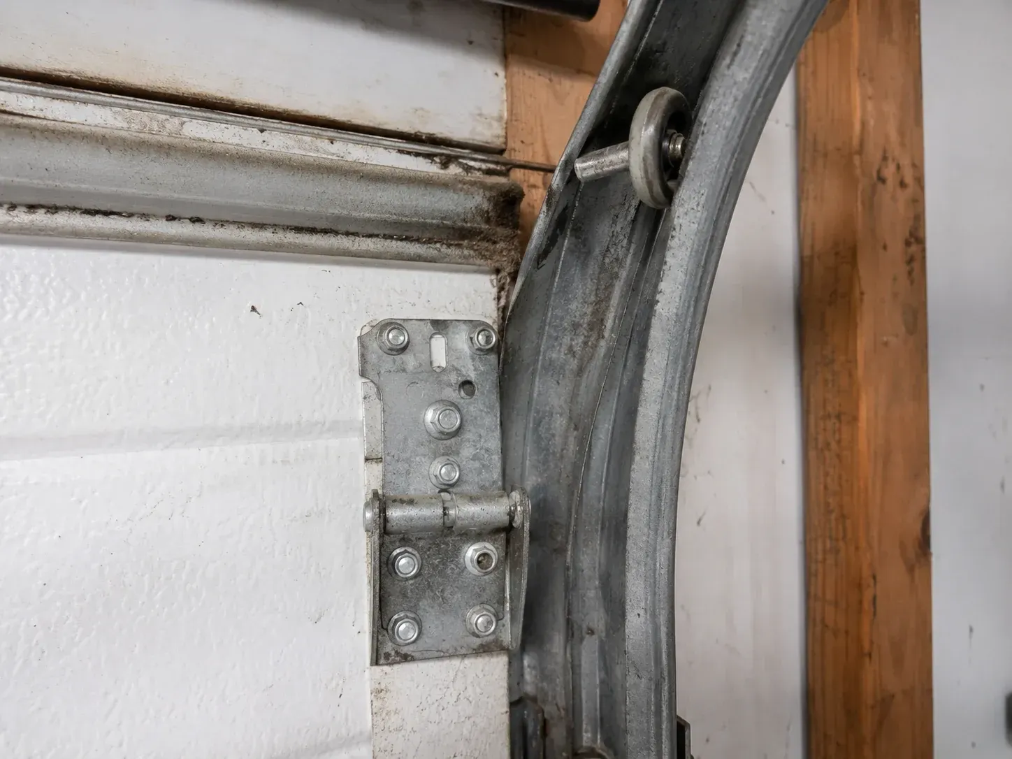 Garage door roller and track hardware needing repair inside a residential garage
