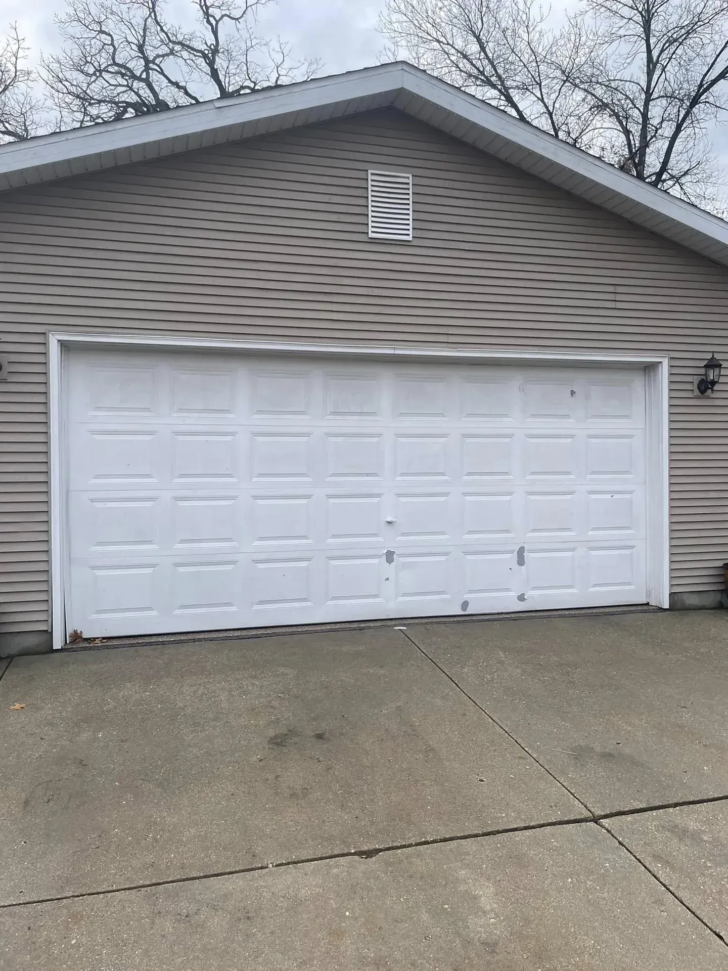 Old, worn white garage door with chalking and paint damage on a home in Roscoe, IL before replacement