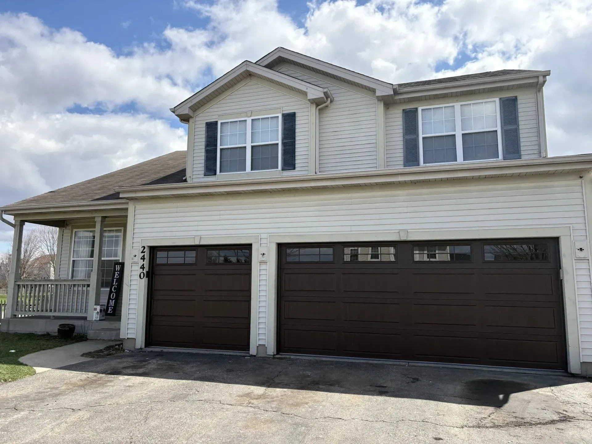 Brown wood-look garage doors with upper windows on a white residential home