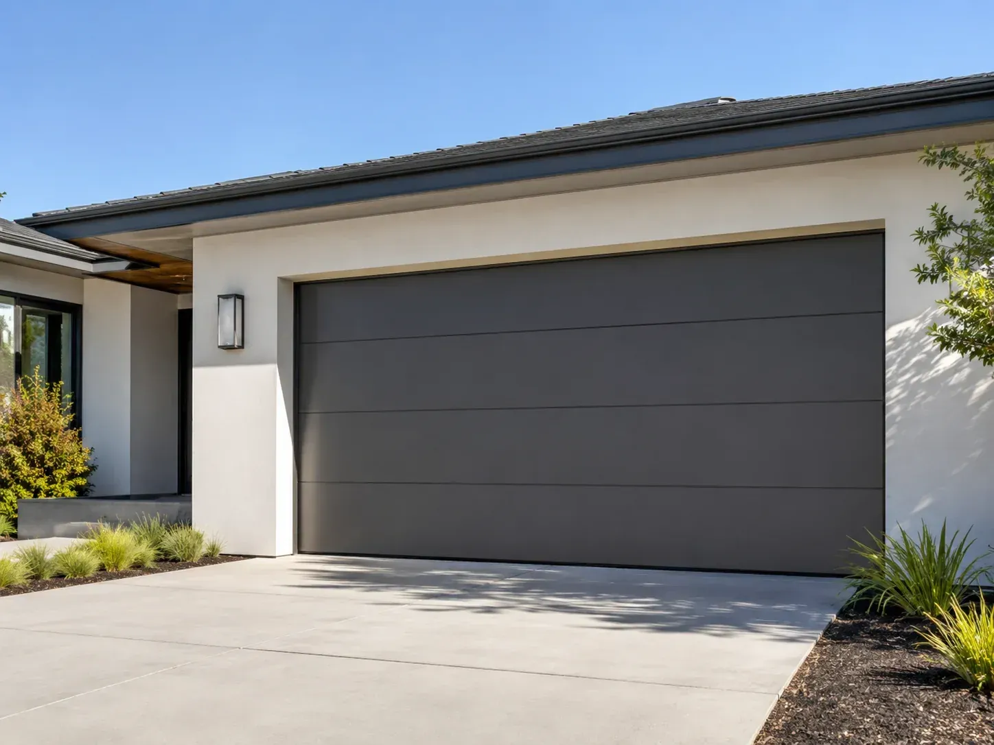 Wood-look steel garage door with upper windows and decorative exterior lighting