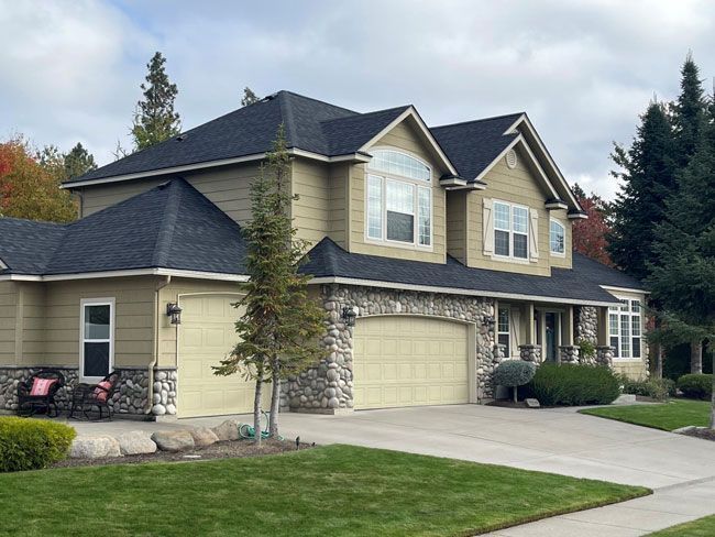 Front view of a beige two-story house with gray trim and a peaked roof Front view of a beige two-story house with gray trim and a peaked roof